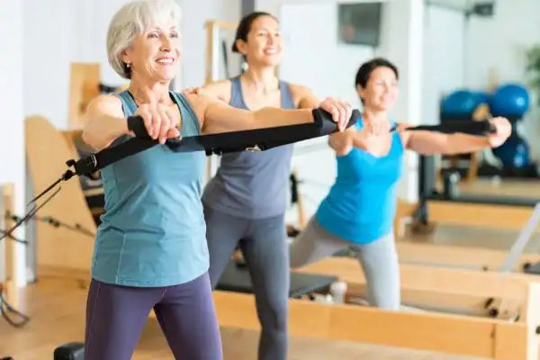 Toning Arms After 60: Empowering Womens Fitness Through Effective Weight Training 2 older woman doing weight training Guildford and resistance in the gym to tone upper arms