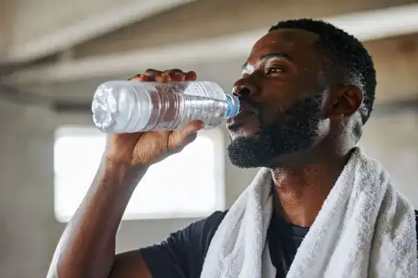 Hydration: The Secret Ingredient for a Toned Stomach and Enhanced Fitness 1 Image of man drinking water to improve hydration Guildford after work out.